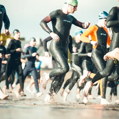 Triathlètes courant vers l’eau au départ